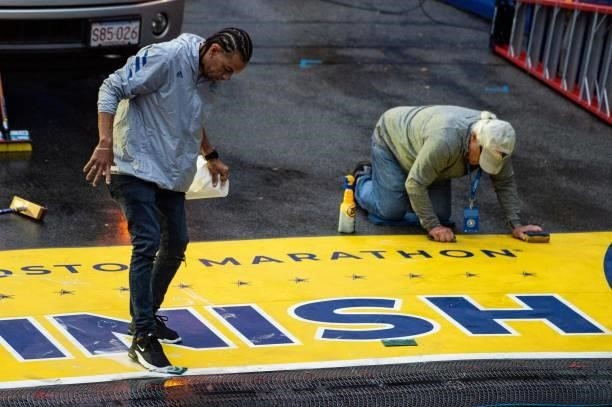 Workers clean the finish line logo before the start of the race during the 125th Boston Marathon in Boston, Massachusetts on October 11, 2021.