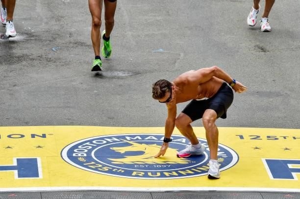 Man touches the finish line after kissing his hand on Boylston Street during the 125th Boston Marathon in Boston, Massachusetts on October 11, 2021.