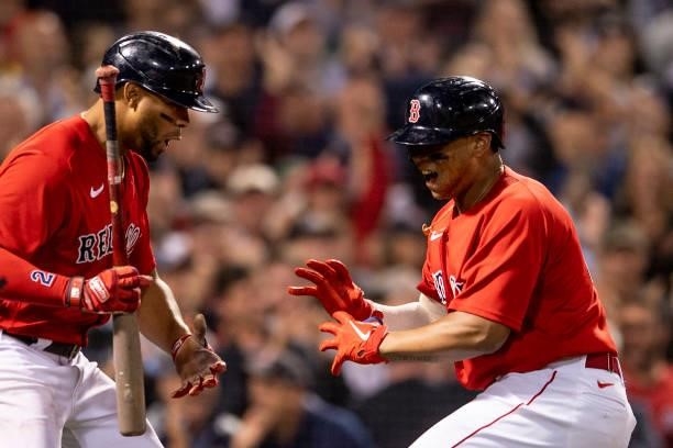 Rafael Devers of the Boston Red Sox reacts with Xander Bogaerts after hitting a three run home run during the third inning of game four of the 2021...