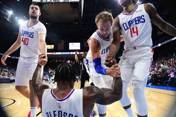 Ivica Zubac, Luke Kennard and Terance Mann of the LA Clippers help up Eric Bledsoe of the LA Clippers during a preseason game against the Minnesota...