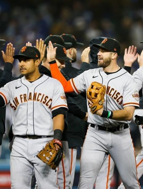 Evan Longoria of the San Francisco Giants hi fives with teammates after the final out beating the Los Angeles Dodgers 1-0 during Game 3 of the NLDS...