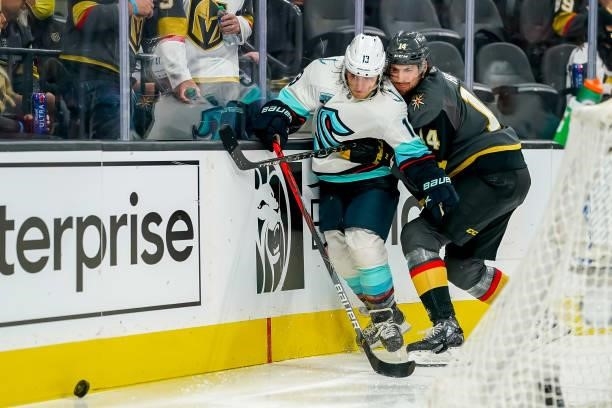Brandon Tanev of the Seattle Kraken and Nicolas Hague of the Vegas Golden Knights battle along the boards as they chase the puck during third period...