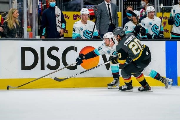 Jared McCann of the Seattle Kraken reaches for the puck along the boards as Chandler Stephenson of the Vegas Golden Knights gives chase during second...