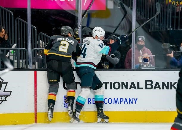Nathan Bastian of the Seattle Kraken avoids a check along the boards from Zach Whitecloud of the Vegas Golden Knights during first period action at...
