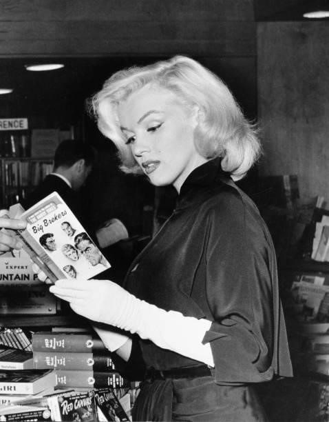 American actress and model Marilyn Monroe reads a copy of Irving Shulman's novel 'The Big Brokers' at a bookstore , Beverly Hills, California, 1953.