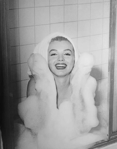 American actress and model Marilyn Monroe , partially covered in soap bubbles and with her hair wrapped in a towel, in a bathtub at the Hotel...