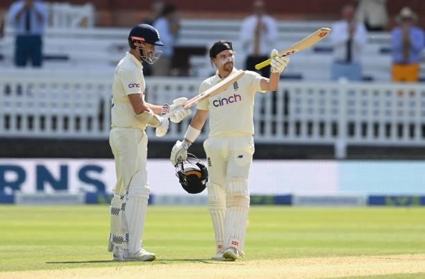 Rory Burns celebrates reaching his century as he stands with James Anderson of England during Day 4 of the First LV= Insurance Test match between...