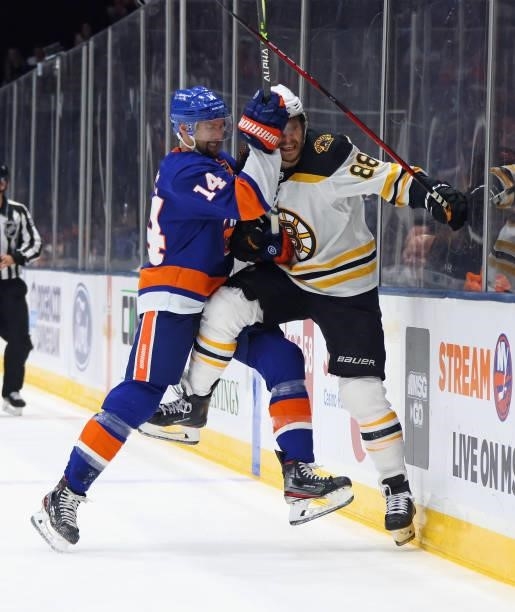 David Pastrnak of the Boston Bruins is checked into the boards by Travis Zajac of the New York Islanders during the first period in Game Four of the...