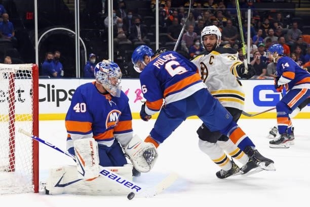 Semyon Varlamov and Ryan Pulock of the New York Islanders defend the net against Patrice Bergeron of the Boston Bruins during the first period in...