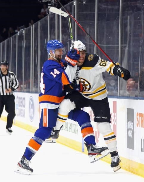 David Pastrnak of the Boston Bruins is checked into the boards by Travis Zajac of the New York Islanders during the first period in Game Four of the...