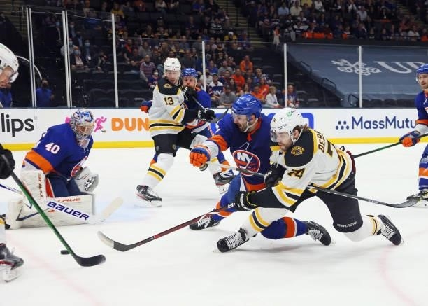 Jake DeBrusk of the Boston Bruins attempts to get a shot off while being checked by Adam Pelech of the New York Islanders during the third period in...