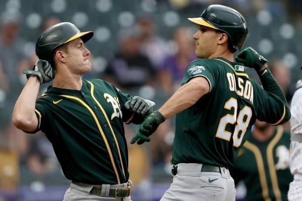 Matt Olson of the Oakland Athletics is congratulated by Mark Canha after hitting a 2 RBI home run against the Colorado Rockies in the first inning at...