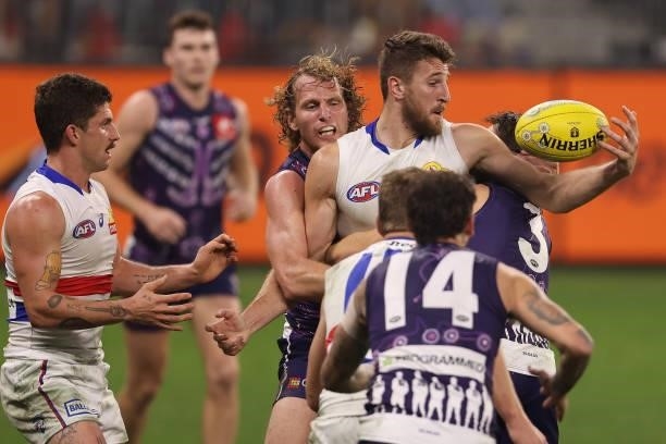 Marcus Bontempelli of the Bulldogs gets tackled by David Mundy and Caleb Serong of the Dockers during the round 12 AFL match between the Fremantle...