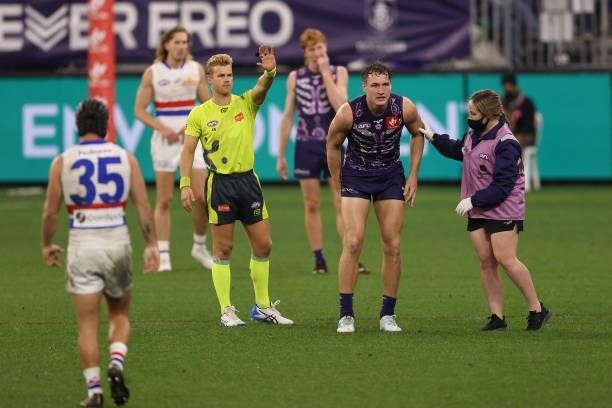 Brennan Cox of the Dockers looks on in the hands of a trainer during the round 12 AFL match between the Fremantle Dockers and the Western Bulldogs at...