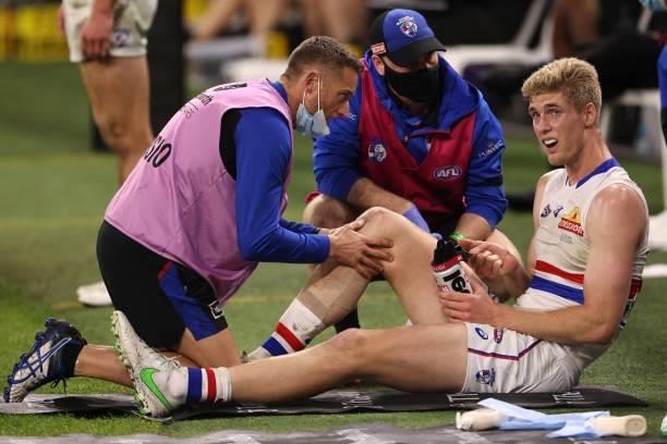 Tim English of the Bulldogs has his right knee assessed by the team physio during the round 12 AFL match between the Fremantle Dockers and the...