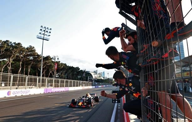 Sergio Perez of Mexico driving the Red Bull Racing RB16B Honda crosses the finish line to win as Red Bull Racing team members celebrate on the...