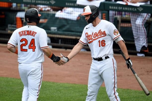 Stewart of the Baltimore Orioles celebrates with Trey Mancini after scoring in the second inning against the Cleveland Indians at Oriole Park at...