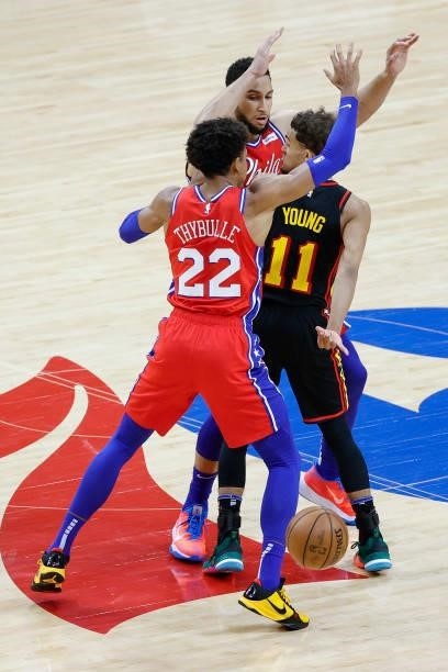 Trae Young of the Atlanta Hawks passes between Ben Simmons and Matisse Thybulle of the Philadelphia 76ers during the fourth quarter during Game One...