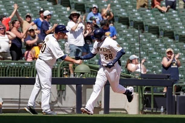 Third base coach Jason Lane of the Milwaukee Brewers congratulates Daniel Robertson of the Milwaukee Brewers on a solo home run in the fifth inning...