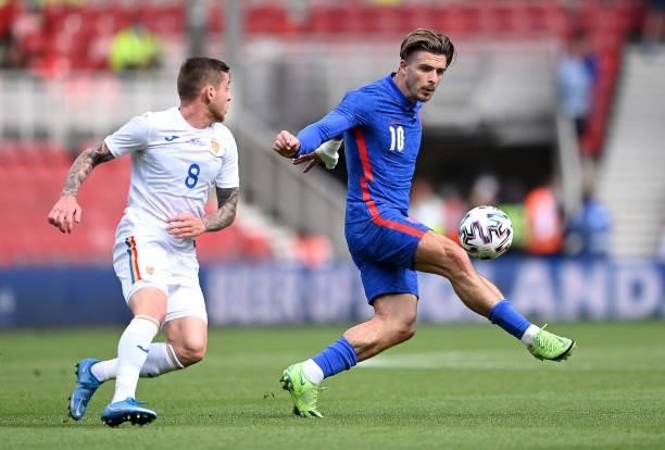 Jack Grealish of England battles for possession with Alexandru Cicaldau of Romania during the international friendly match between England and...