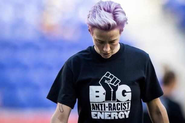 Megan Rapinoe of OL Reign with her head down wears a tee shirt that says Big Anti-Racist Energy with a Black Power Fist on it as she warms up before...