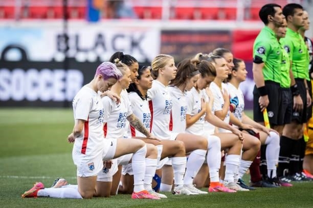 The starting lineup for OL Reign including Megan Rapinoe of OL Reign kneel for the national anthem before the match against NJ/NY Gotham FC at Red...