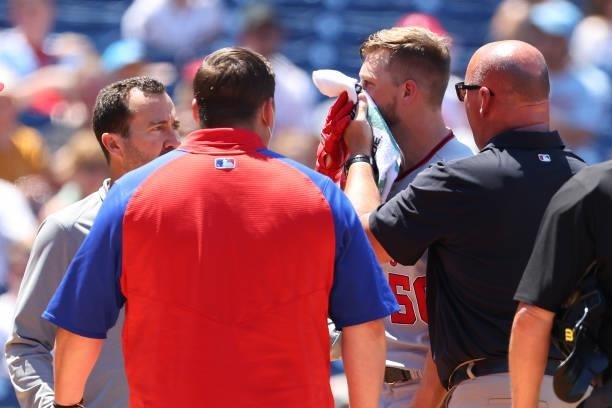 Austin Voth of the Washington Nationals has a compress held to his face after getting hit by a pitch on an attempted bunt against the Philadelphia...