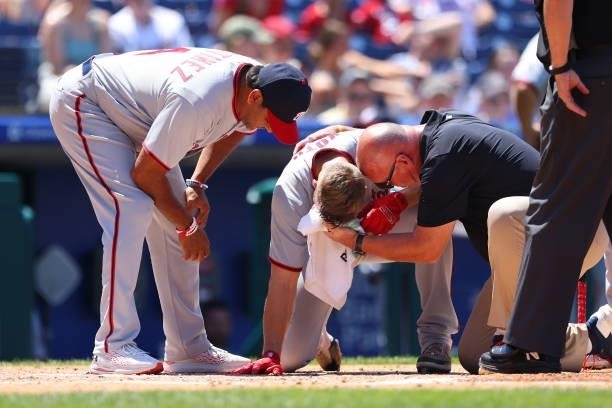 Austin Voth of the Washington Nationals has a compress held to his face after getting hit by a pitch on an attempted bunt against the Philadelphia...