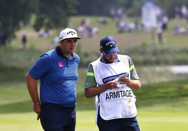Marcus Armitage of England chats with his caddie on the 18th hole during Day Three of The Porsche European Open at Green Eagle Golf Course on June...