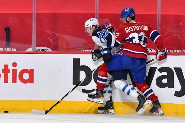 Erik Gustafsson of the Montreal Canadiens pins Mason Appleton of the Winnipeg Jets against the boards during the third period in Game Three of the...