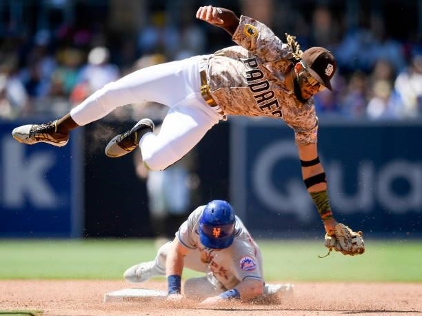Billy McKinney of the New York Mets steals second base as Fernando Tatis Jr. #23 of the San Diego Padres leaps over fielding the throw in the sixth...