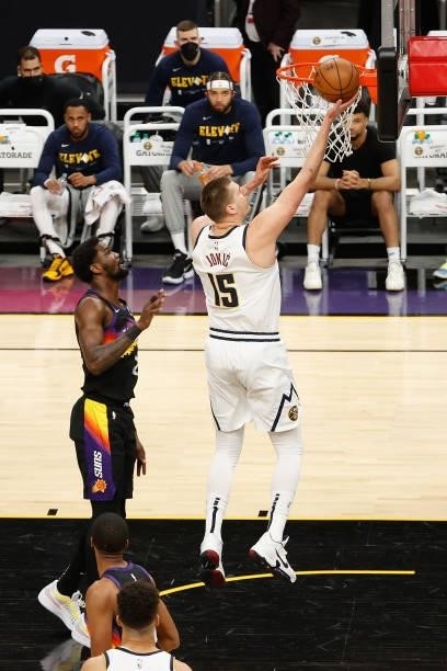 Nikola Jokic of the Denver Nuggets lays up a shot past Deandre Ayton of the Phoenix Suns during the first half in Game One of the Western Conference...