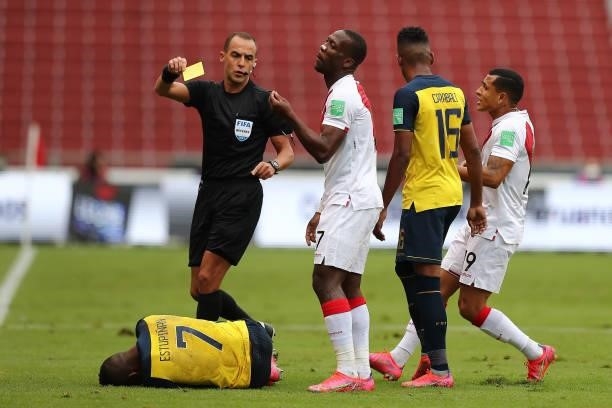 Referee Esteban Ostojich shows a yellow card to to Luis Advíncula of Peru after a foul to Pervis Estupiñan of Ecuador during a match between Ecuador...
