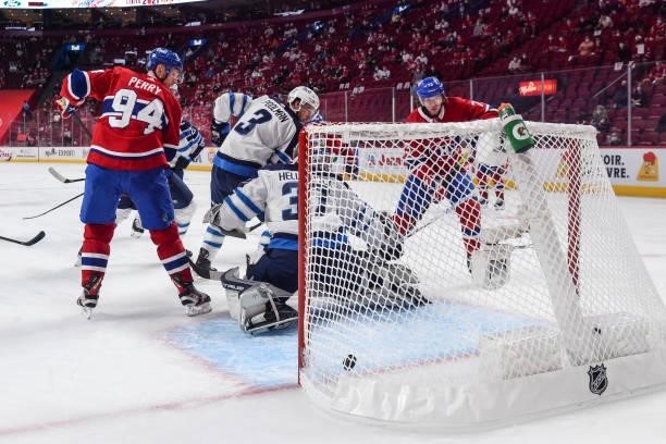 Goaltender Connor Hellebuyck of the Winnipeg Jets allows a goal with Corey Perry and Tyler Toffoli of the Montreal Canadiens near the net during the...