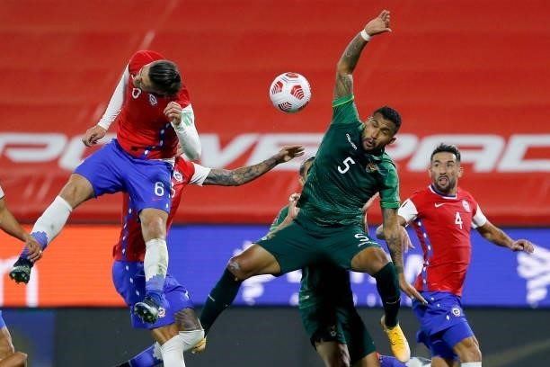 Francisco Sierralta of Chile jumps for the ball with Adrián Jusino of Bolivia during a match between Chile and Bolivia as part of South American...