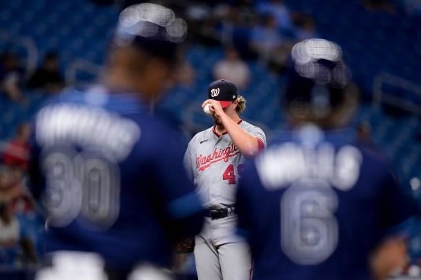 Sam Clay of the Washington Nationals reacts on the mound as Taylor Walls and first base coach Ozzie Timmons of the Tampa Bay Rays look on from first...