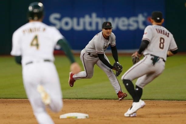 Josh Rojas of the Arizona Diamondbacks fields the ball and passes it to Ildemaro Vargas to get the out on Chad Pinder of the Oakland Athletics in the...