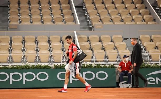 Novak Djokovic of Serbia walks back on court after play was suspended with fans being made to leave the stadium due to government curfew restrictions...