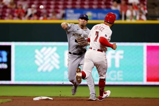 Jace Peterson of the Milwaukee Brewers turns a double play past Eugenio Suarez of the Cincinnati Reds in the seventh inning at Great American Ball...