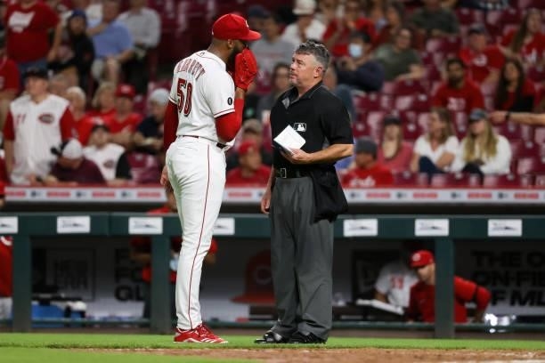 Amir Garrett of the Cincinnati Reds talks with umpire Rob Drake in the eighth inning against the Milwaukee Brewers at Great American Ball Park on...