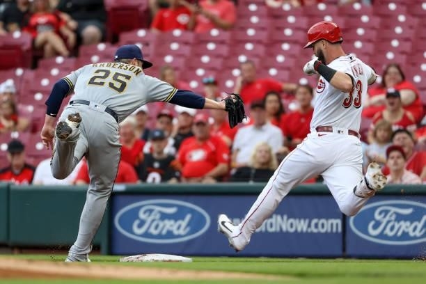 Jesse Winker of the Cincinnati Reds reaches first base for a single past Brett Anderson of the Milwaukee Brewers in the first inning at Great...