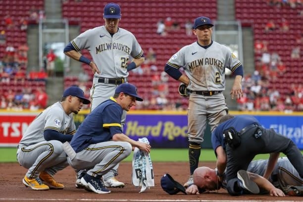 Teammates look on as Travis Shaw of the Milwaukee Brewers is attended to after being injured in the second inning against the Cincinnati Reds at...