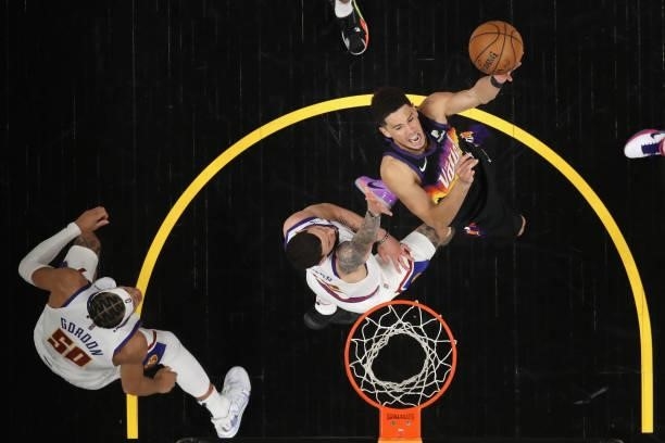Devin Booker of the Phoenix Suns attempts a shot over Austin Rivers of the Denver Nuggets during the first half in Game Two of the Western Conference...