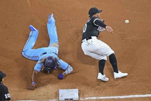 Vladimir Guerrero Jr. #27 of the Toronto Blue Jays advances to third base on a wild pitch as Yoan Moncada of the Chicago White Sox takes the late...