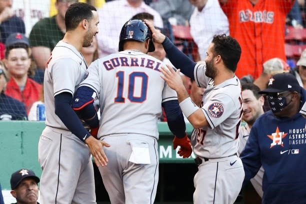 Yuli Gurriel high fives Carlos Correa of the Houston Astros as he returns to the dugout after hitting a solo home run in the second inning of a game...