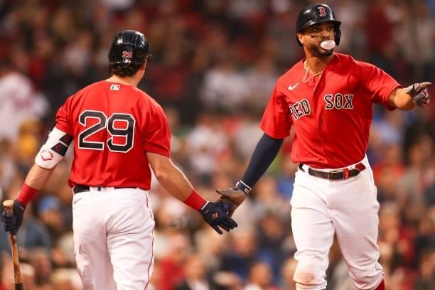 Xander Bogaerts of the Boston Red Sox high fives Bobby Dalbec of the Boston Red Sox after scoring in the third inning of a game against the Houston...