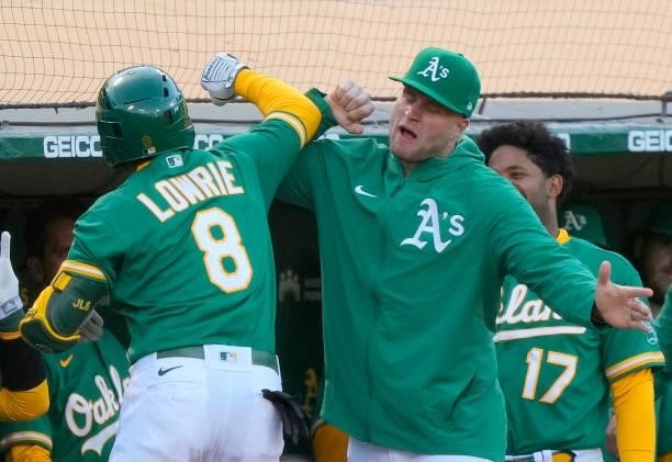 Jed Lowrie of the Oakland Athletics is congratulated by Seth Brown after hitting a solo home run against the Kansas City Royals in the bottom of the...