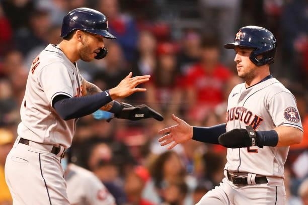Carlos Correa high fives Alex Bregman of the Houston Astros after both players score in the third inning of a game against the Boston Red Sox at...