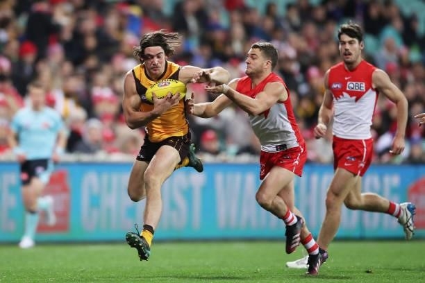 Jai Newcombe of the Hawks is challenged by Tom Papley of the Swans during the round 13 AFL match between the Sydney Swans and the Hawthorn Hawks at...
