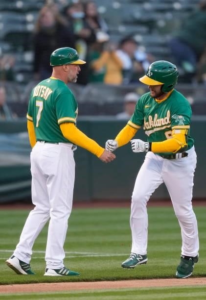 Jed Lowrie of the Oakland Athletics is congratulated by third base coach Mark Kotsay after Lowrie hit a solo home run against the Kansas City Royals...